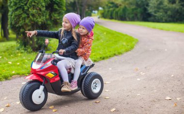 yeşil park oyuncak motosiklet üzerinde oturan küçük sevimli kız