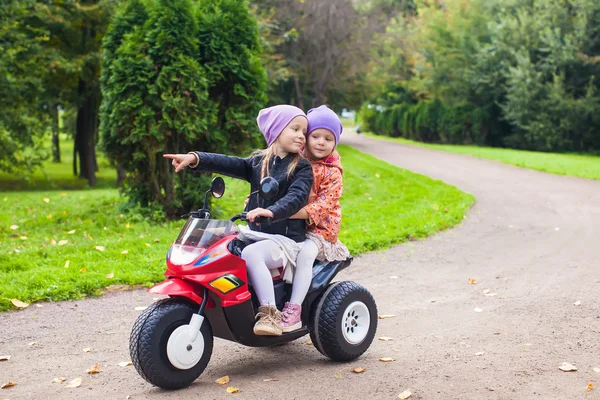 Adorables niñas montando en bicicleta para niños en el parque verde —  Fotos de Stock