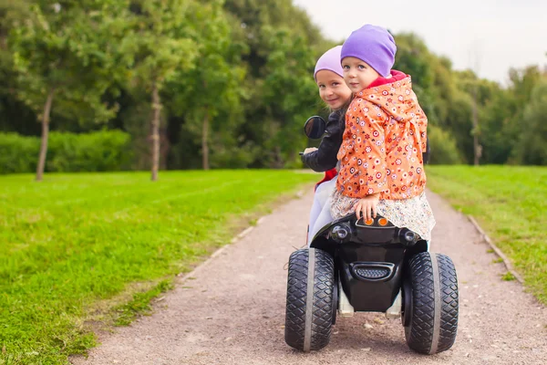 Portrait of little girls ride a motorbike outdoors — Stock Photo, Image
