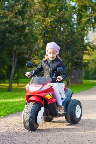 Pequena menina adorável se divertindo em sua motocicleta de brinquedo — Fotografia de Stock
