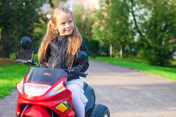 Portrait de heureuse petite fille rock en veste en cuir assise sur sa moto jouet — Photo