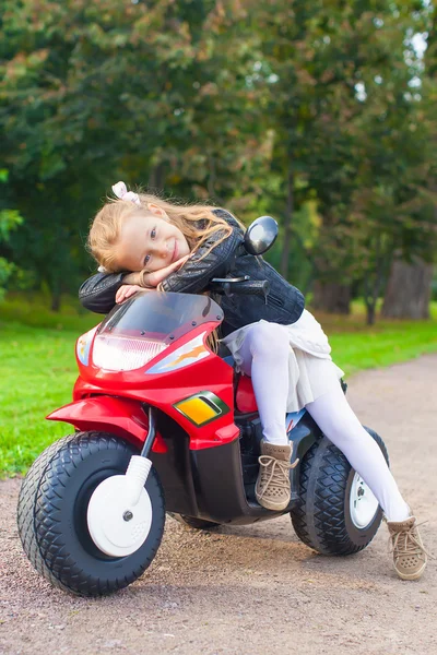 Beautiful little girl having fun on her toy motorcycle — Stock Photo, Image