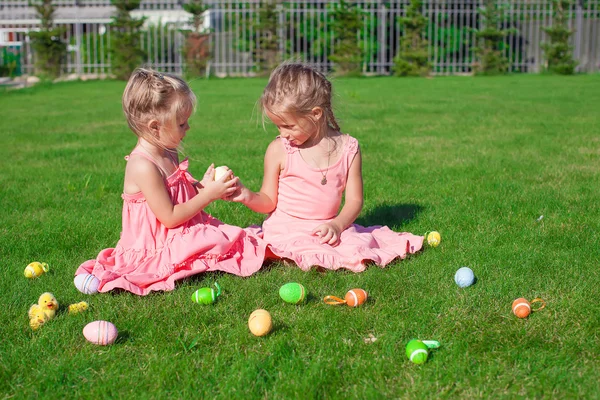 Två bedårande små flickor leker med påskägg på grönt gräs — Stockfoto