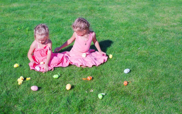 Yeşil çimenlerin üzerinde Paskalya yumurtaları ile oynarken iki sevimli küçük kız — Stok fotoğraf