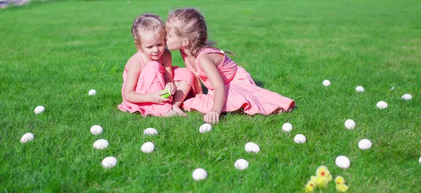Старшая сестра целуется моложе на зеленой поляне пасхальных яиц — стоковое фото