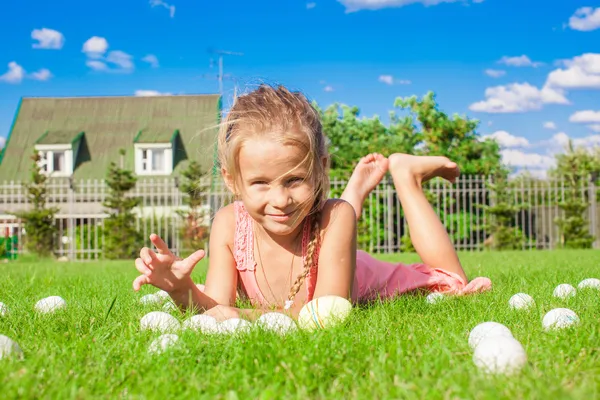 Little adorable girl playing with white Easter eggs in the yard — Stock Photo, Image