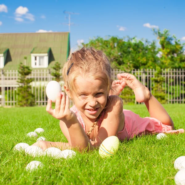Mooi meisje vindt Pasen eieren op groen gras — Stockfoto