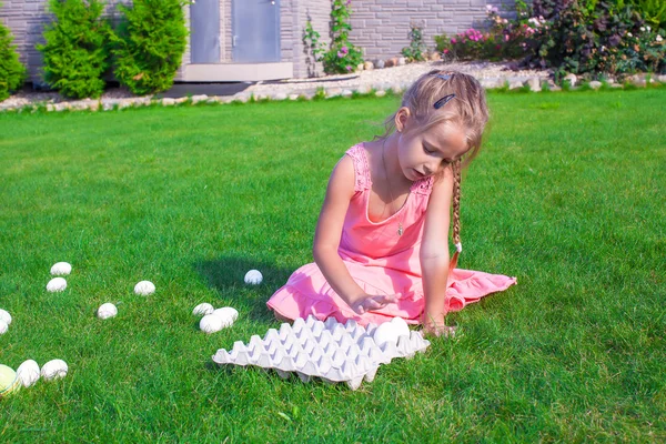 Little beautiful girl is preparing for Easter with a tray of white eggs — Stock Photo, Image