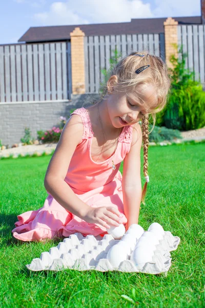 Adorable little girl preparing for Easter with a tray of white eggs — Stock Photo, Image