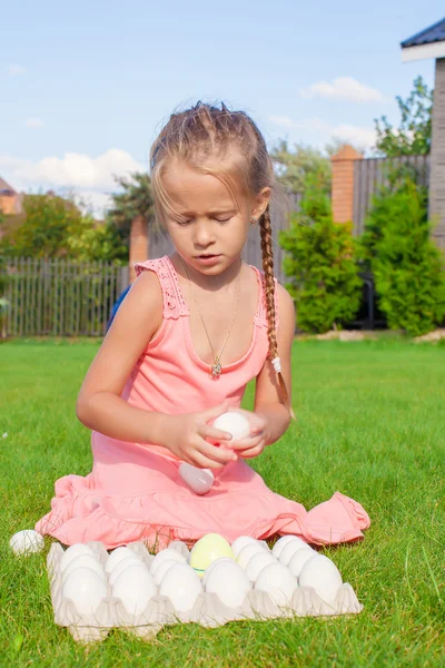 Retrato de menina bonito brincando com ovos brancos de Páscoa na grama verde — Fotografia de Stock