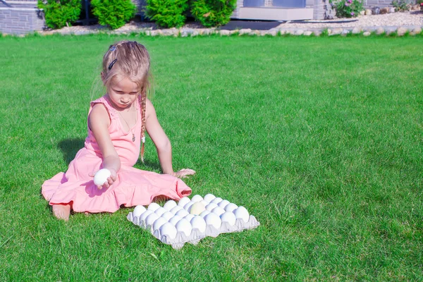 Αξιολάτρευτο κοριτσάκι που κρατάει ένα λευκό αυγό του Πάσχα στην αυλή της — Φωτογραφία Αρχείου
