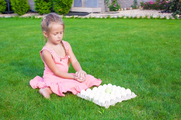Gadis kecil yang cantik memegang telur Paskah hijau duduk di luar ruangan — Stok Foto