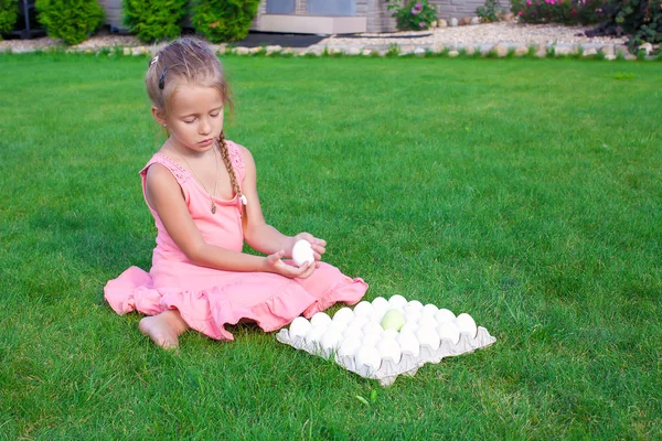 Adorable petite fille tenant vert oeuf de Pâques assis en plein air — Photo