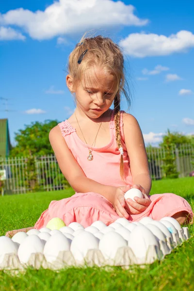 Encantadora niña sosteniendo un huevo de Pascua blanco en su patio —  Fotos de Stock