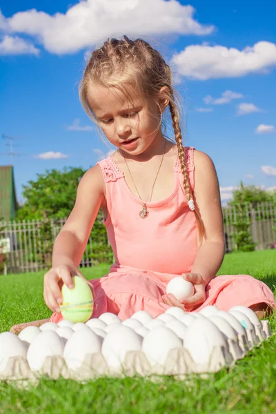 Schattig meisje spelen met witte paaseieren in de tuin — Stockfoto