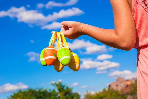 Primeros planos de una niña pequeña sosteniendo coloridos huevos de Pascua de fondo el cielo azul —  Fotos de Stock