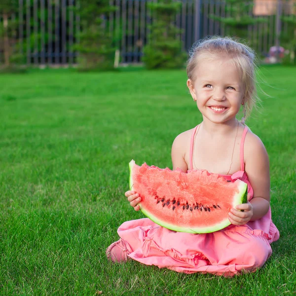 Little girl with big piece of watermelon in hands on green grass — Stock Photo, Image