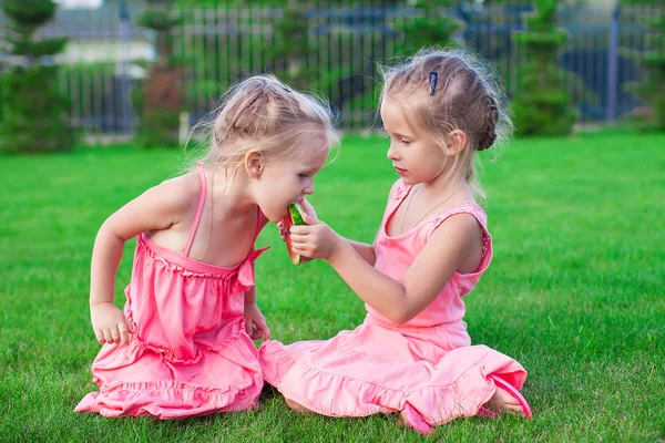 Older sister feeding younger piece of watermelon on a hot summer day — Stock Photo, Image