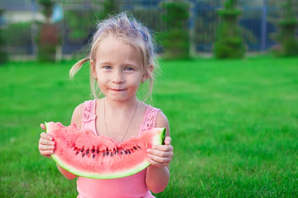 Adorable little toddler sitting on the grass with a piece of watermelon — Stock Photo, Image