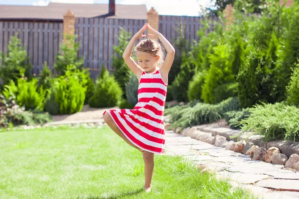 Liten bedårande flicka stående i en yogaställning på ett ben — Stockfoto