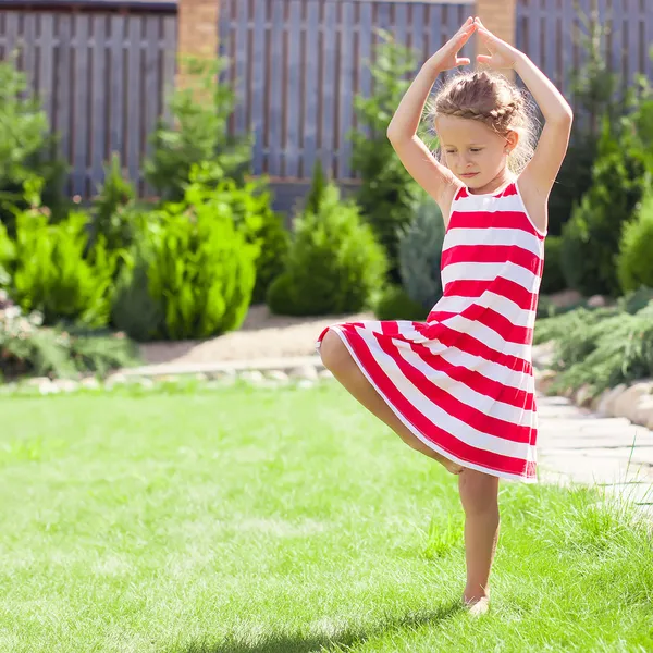 Liten bedårande flicka stående i en yogaställning på ett ben — Stockfoto