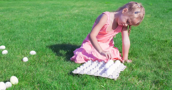 Little beautiful girl is preparing for Easter with a tray of white eggs — Stock Photo, Image