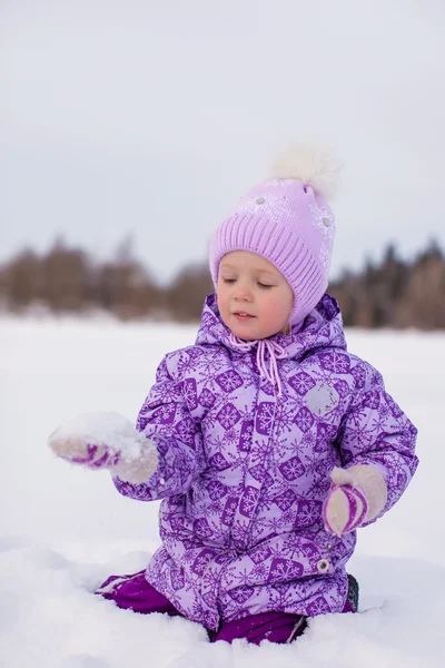 Fröhliches kleines Mädchen hat Spaß auf dem Schnee an einem sonnigen Wintertag — Stockfoto