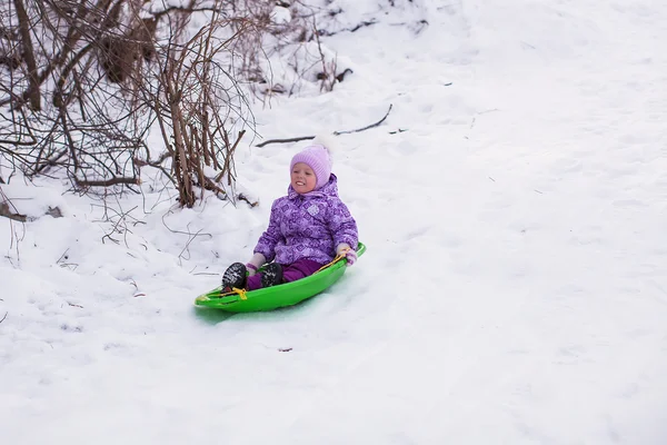 Adorable little girl sledding in snowy forest — Stock Photo, Image