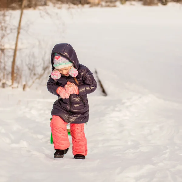 Kleines Mädchen zieht an warmen Wintertagen einen Schlitten — Stockfoto