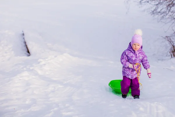 Kleines Mädchen zieht an warmen Wintertagen einen Schlitten — Stockfoto