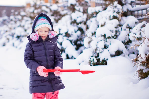 Kleines Mädchen spielt mit roter Schaufel im Garten — Stockfoto
