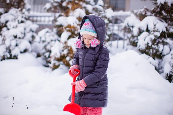 Menina brincar com pá de neve em um dia de inverno — Fotografia de Stock