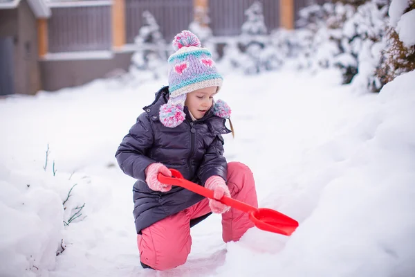 Little adorable girl play with snow shoveling on a winter day — Stock Photo, Image
