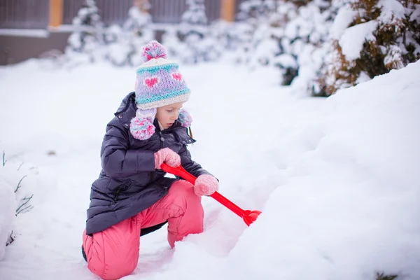 Bambina giocare con la neve spalare in una giornata invernale — Foto Stock