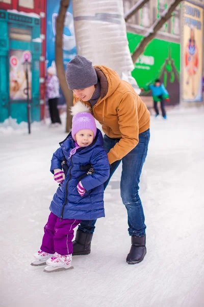 Kleines glückliches Mädchen mit jungem Vater haben Spaß auf der Eisbahn — Stockfoto