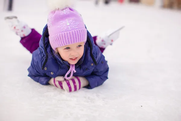 Adorable little girl sitting on ice with skates after the fall — Stock Photo, Image