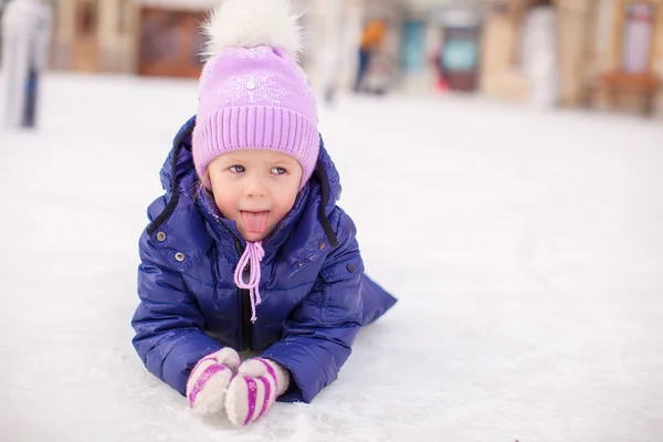 Entzückendes kleines Mädchen liegt nach dem Sturz auf der Eisbahn — Stockfoto
