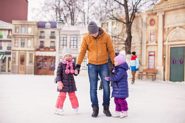 Little girls with young father enjoying skating