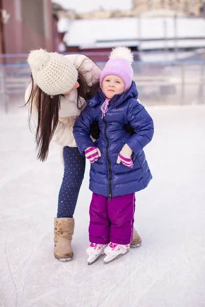 Glücklich liebenswertes kleines Mädchen und junge Mutter lernen Schlittschuhlaufen — Stockfoto