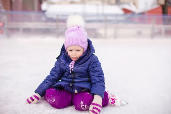 Triest meisje zitten op ijs met schaatsen na de val — Stockfoto