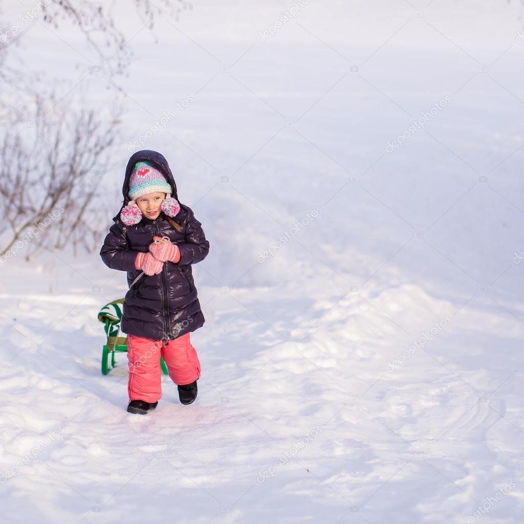 Little girl goes sledding on a warm winter day