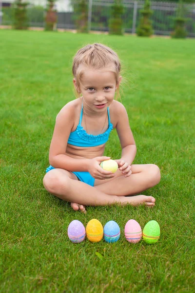 Paskalya yumurtaları onun bahçesinde çimenlerin üzerinde küçük kız — Stok fotoğraf