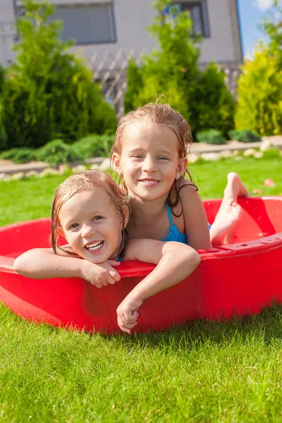 Two little happy girls having fun in small pool outdoor on summer day — Stock Photo, Image