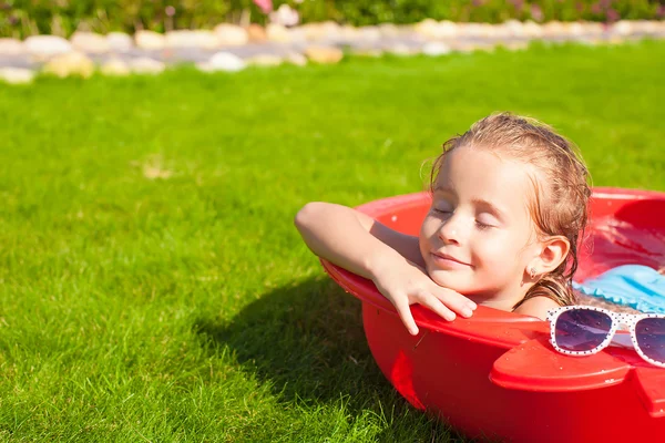 Portrait of relaxing adorable little girl enjoying her vacation in small pool outdoor — Stock Photo, Image