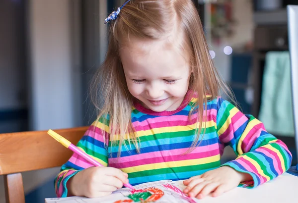 Adorable little girl draws paints sitting at the table — Stock Photo, Image