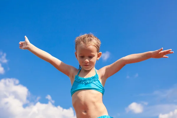 Entzückendes kleines Mädchen breitet die Arme aus Hintergrund des blauen Himmels — Stockfoto