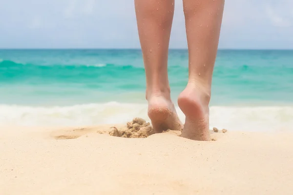 Women's beautiful smooth legs on white sand beach — Stock Photo, Image