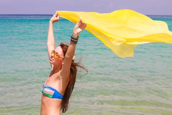 Menina bonita segurando tecido amarelo no vento em férias na praia — Fotografia de Stock