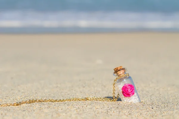 Small bottle in white sandy beach background the turquoise sea — Stock Photo, Image