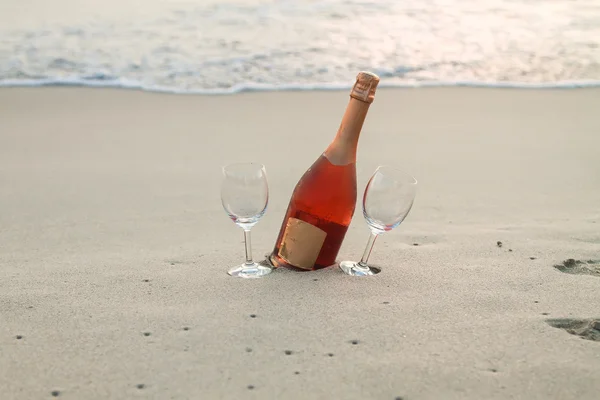 Bottle of red wine and two glasses on the white sandy beach — Stock Photo, Image